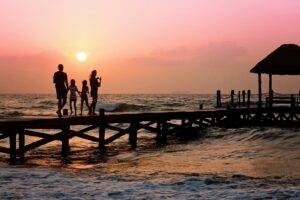 Family walking across a pier in a tropical location at sundown.