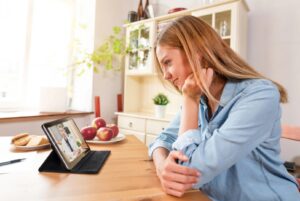 Woman on a telehealth call with a doctor while sitting at a table in her home.