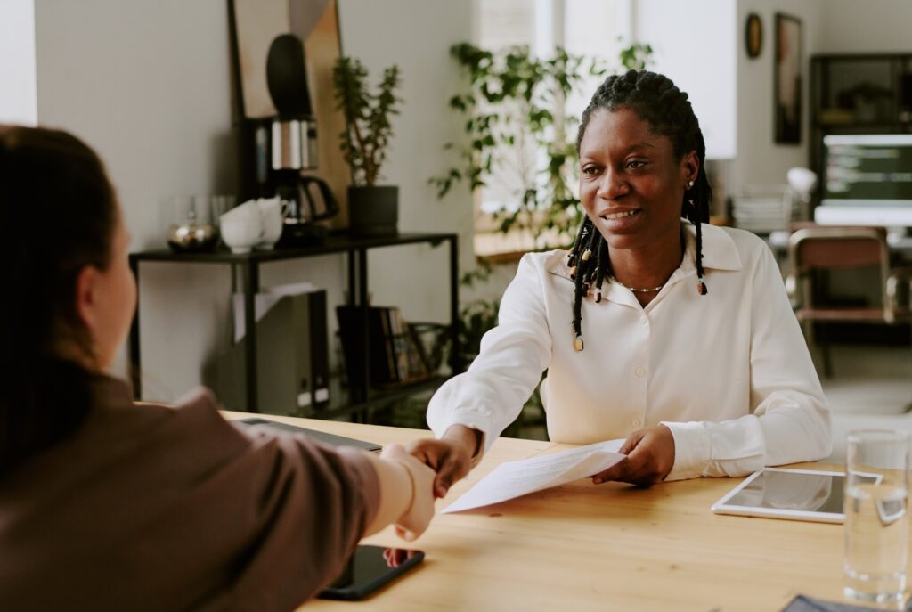 Two young professionals are shaking hands in a modern office setting